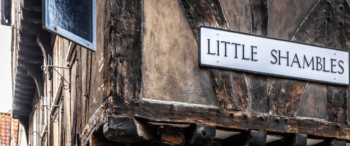 Image of an old wall with the sign 'Little Shambles' printed on it